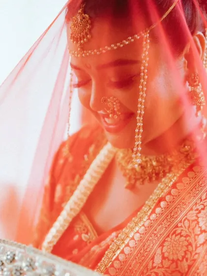 A beautiful, soft-focus portrait of the bride, her face illuminated through her red veil. This artistic shot is full of warmth and emotion.