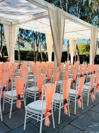 Elegant guest seating with peach-colored drapes for an outdoor ceremony. Simple touches like this can elevate the entire look of the venue.