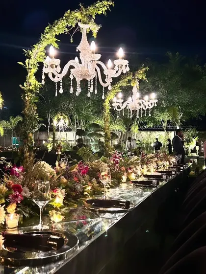 The mirrored table reflects the candlelight and the sky, adding to the magic of this luxurious outdoor dining experience.