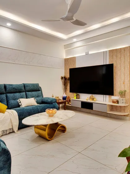 The living room in our Kerala-inspired home, featuring a comfortable teal sofa and a modern TV unit with fluted panel details.