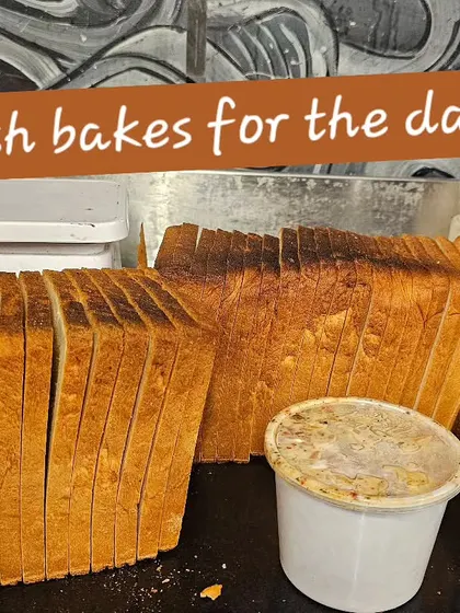 Sliced sandwich bread is lined up on our counter beside tubs, ready for the day's café bread orders.