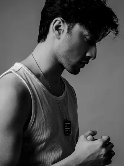 A pensive black and white profile shot of Lakshya in the classic tank top look.