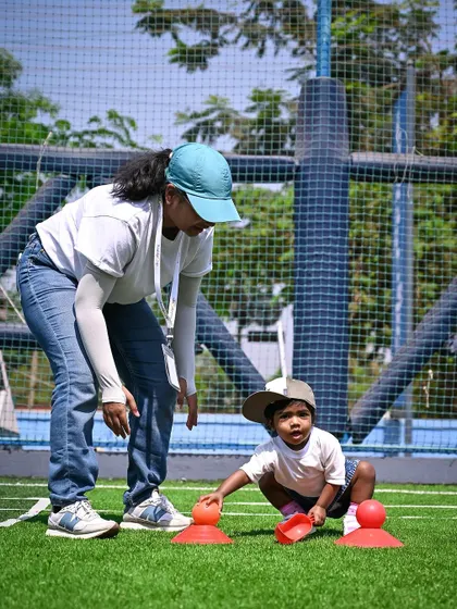 A teacher guides a toddler through a scooping and sorting activity.