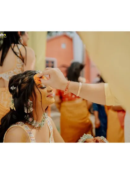 A gentle moment during the Haldi ceremony. This close-up of the bride, Sakshi, having flowers and haldi applied is a beautiful, traditional shot filled with warmth.