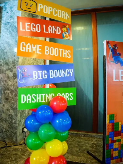 A colorful, pixelated signpost for a LEGO-themed party, directing guests to 'Lego Land', 'Big Bouncy', and 'Dashing Cars'.