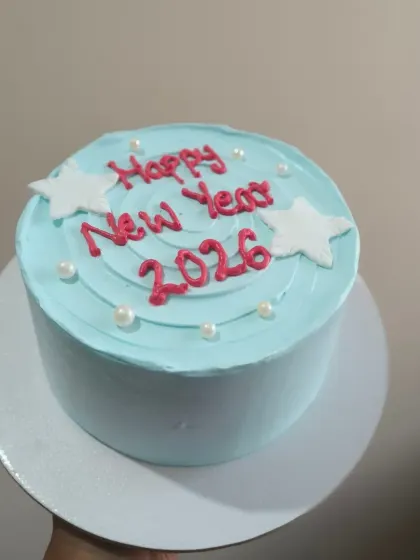 A simple and cute New Year's cake with a "Happy New Year 2026" message. This light blue cake is decorated with little stars and pearls for a touch of celebration.