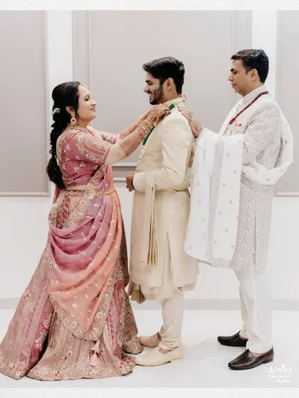 The groom's sister and father help him with his final accessories, a beautiful family moment filled with love.