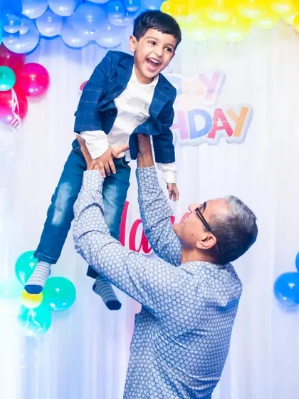 The joy of a grandfather playing with his grandson. This heartwarming action shot, set against a colorful balloon backdrop, is a precious memory from a third birthday party.