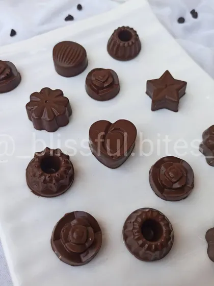 A glimpse of my homemade chocolate selection, perfect for gifting or a personal indulgence. You can see the different shapes and moulds I use, from hearts to flowers, each filled with flavours like hazelnut, almond, and caramel.