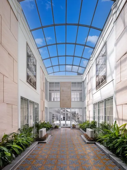 Another view of the sunlit courtyard in The Grand Alabaster, where the glass roof turns the sky into a ceiling. Lined with lush plants and stone walls, it serves as a tranquil core for the entire home.