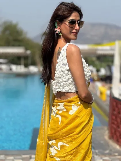 A view of the back of the textured blouse, which adds an element of surprise to this saree look. Paired with floral earrings, this outfit is a perfect example of modern ethnic styling.