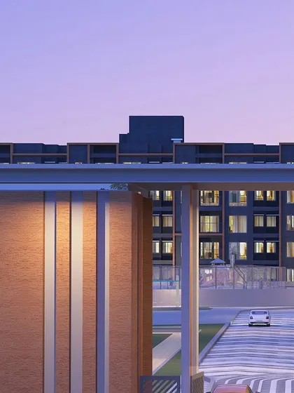 A view through a modern gateway at dusk, framing the illuminated windows of the residential block beyond and creating a sense of depth and invitation.