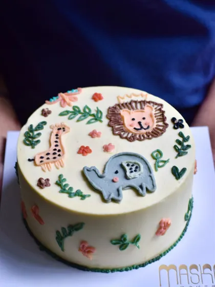 A custom birthday cake for a little animal lover, featuring a hand-piped jungle scene with a friendly lion, giraffe, and elephant. We create whimsical and fun children's birthday cakes using only delicious buttercream, ensuring they taste as good as they look.