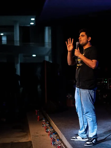 Samay Raina on stage at IIM Trichy, with the audience visible in the background.