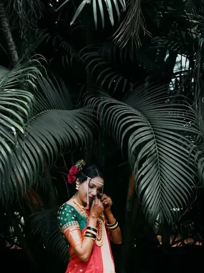 An emotional, candid moment of the bride wiping a tear, captured beautifully against a dark, leafy background.