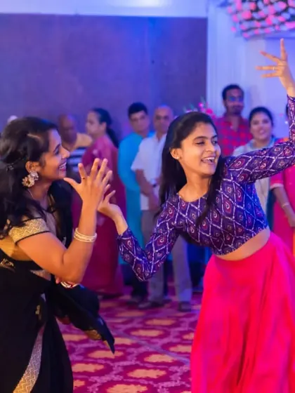 Two friends share a laugh and a dance move on stage. The friendships celebrated during a sangeet are just as important as the couple's love story.