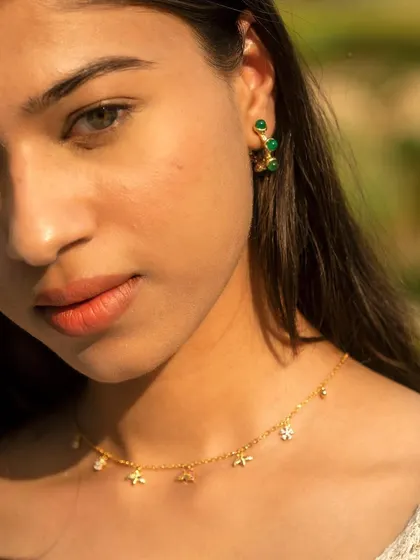Elegance is in the details. A close-up of a model wearing my emerald hoop earrings and a delicate rainbow charm choker.
