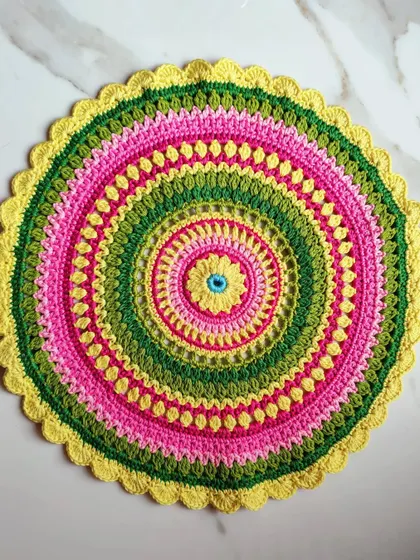 A top-down view of the Viola mandala, showing its perfectly circular shape and the variety of stitches used to create the pattern, including puff stitches and open lacework.