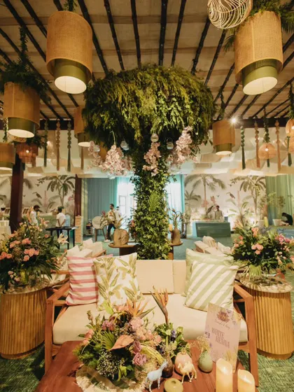 The lounge seating at the tropical Mehendi, featuring rattan furniture, printed cushions, and lush greenery. Every detail was curated to match the bride's vision for a chic kick-off party.