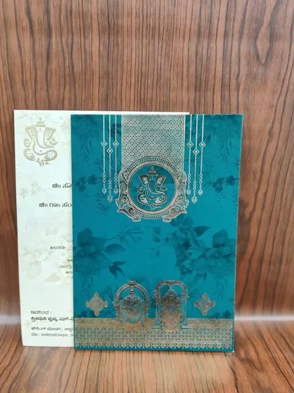 This teal and gold invitation features a prominent Ganesha emblem, blending a modern color with timeless divine blessings.
