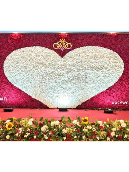 A dramatic reception backdrop with a giant heart made of white flowers against a wall of red flowers.
