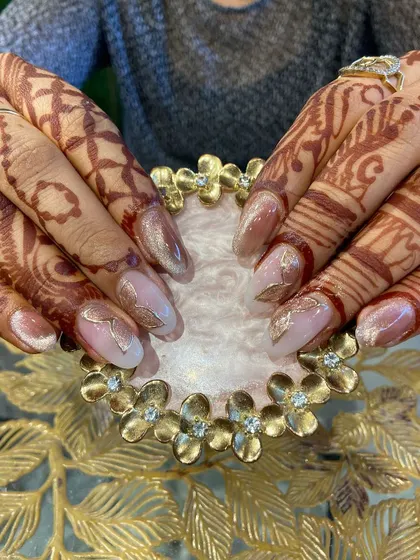 A beautiful cat-eye effect nail design with gold leaf accents, perfectly matching the client's bridal henna.