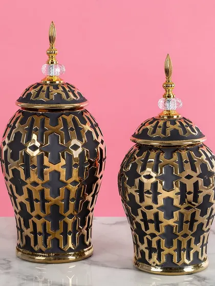 These black and gold vases feature a bold, geometric cutout pattern. They are a perfect example of modern design, adding texture and visual interest to any tabletop.