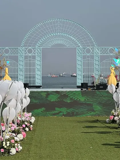 A wide view of the 'Dancing Dolls' varmala stage, set against the open sea, designed to frame the view without obstructing it.