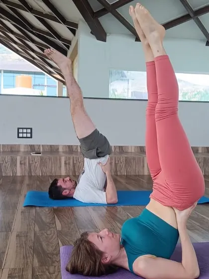 A couple practices Sarvangasana (Shoulder Stand) together. Yoga can be a wonderful shared experience, and our classes welcome individuals, couples, and groups seeking to connect through wellness.