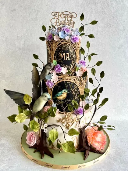 An enchanted garden theme for a special birthday. This three-tiered cake features hand-painted panels, sculpted branches, and delicate sugar birds and flowers. It was a labour of love.