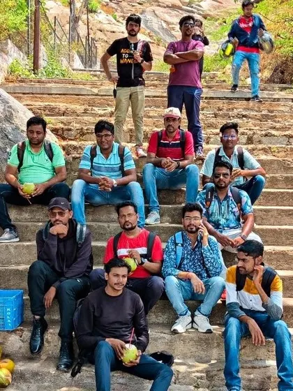 A corporate team relaxes on the steps of Gudibande fort, enjoying fresh coconut water after their climb.