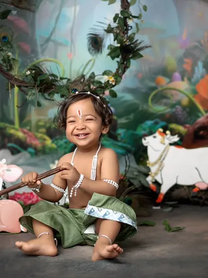 A happy little Krishna in a magical forest setting. The custom backdrop and props create an enchanting world for your child to explore during their themed photoshoot.