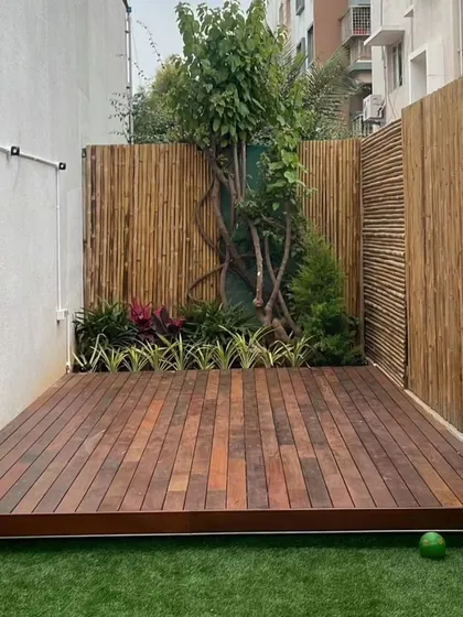 A close-up of a premium Brazilian Ipe wood deck set against a natural bamboo fence. Ipe wood is known for its incredible durability and rich color, making it a fantastic long-term investment for a luxurious and low-maintenance outdoor floor.