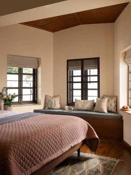 A cozy bedroom in the Coonoor villa, complete with a built-in window seat that offers a perfect spot for reading while enjoying views of the Nilgiri hills.
