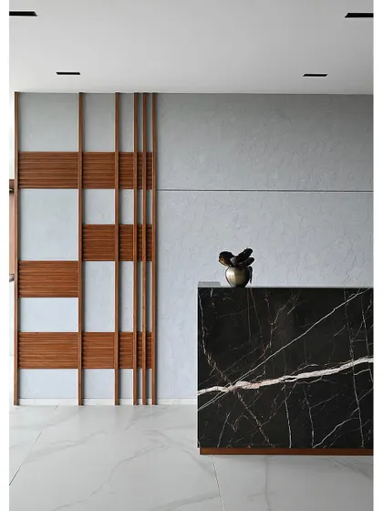 A minimalist composition of the black marble reception desk against a paneled wall with wood accents. This image highlights the clean lines and material contrast that define the project's modern aesthetic.