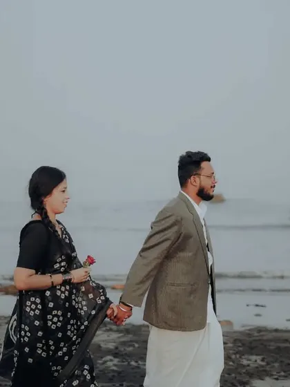 A walking shot along the water's edge, capturing a quiet and contemplative moment from their pre-wedding session.