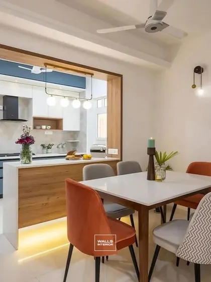 This open kitchen features a peninsula with an under-lit countertop that also serves as a breakfast bar and separates the kitchen from the dining area. The blue and white cabinets are framed with wood for a cohesive look.