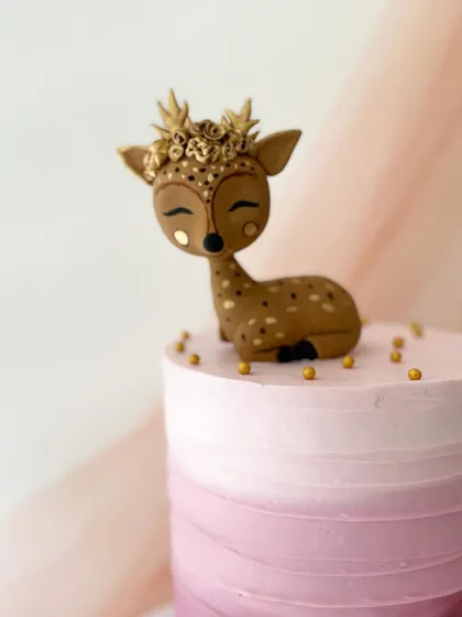 A close-up of the beautiful golden deer topper, showing the delicate details of the crown and the sweet expression.