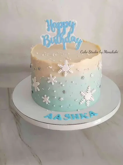 A Frozen themed birthday cake with a wintery feel. This no-fondant cake has a blue ombre effect and is decorated with delicate snowflakes.