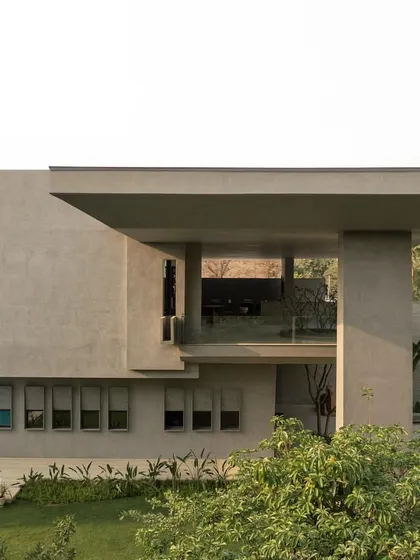 Views of the home from the garden, showing how the monumental concrete forms are softened by the surrounding greenery. The design creates a constant interplay between the architecture and the landscape.