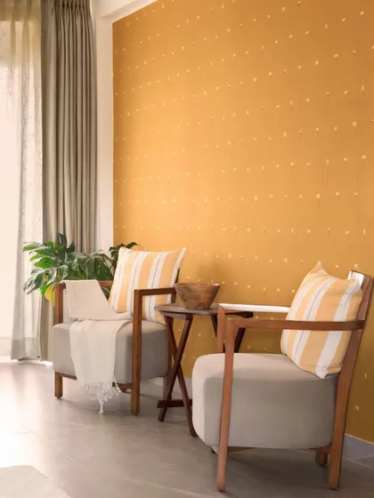 This quiet corner in one of the bedrooms features a mustard-yellow wall with a subtle hand-painted pattern. The simple wooden armchairs create a perfect spot for morning coffee or quiet conversation.