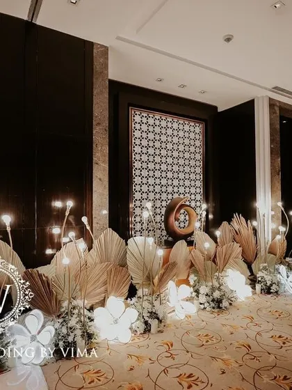 A classic and elegant reception setup symbolizing everlasting love. The stage features a modern, minimalist backdrop with custom monograms, floral arrangements, and soft lighting.