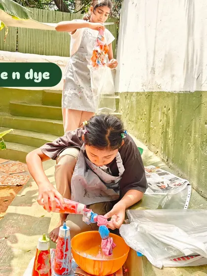 A child carefully applies dye to a tied t-shirt, her focus showing the pride and care she is putting into creating something to help the animals.