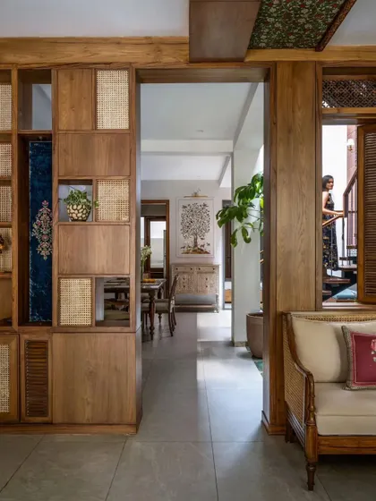 A custom-designed shelving unit combines wood and cane, providing storage while also acting as a beautiful partition between spaces.