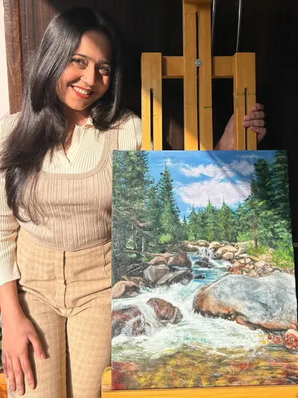 Me with my landscape oil painting. I'm really proud of how the water and trees turned out in this piece.