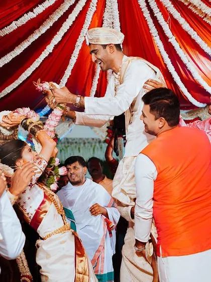 The playful and joyous moment of the garland exchange, with the groom lifted high by his friends and family.
