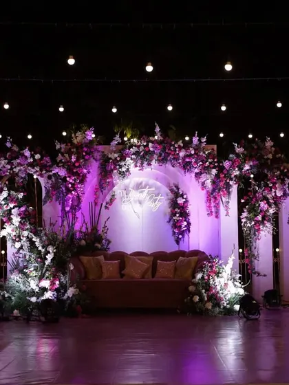 We use dramatic lighting to transform our stage designs at night. Here, purple uplighting completely changes the mood of the reception stage, creating a vibrant and energetic atmosphere perfect for a Sangeet party.