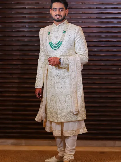 This is a complete groom's look I designed. It features a cream sherwani in a computerized fabric with intricate katdana work, layered over an anarkali kurta and chudidar, and styled with a matching dupatta and mojari shoes.