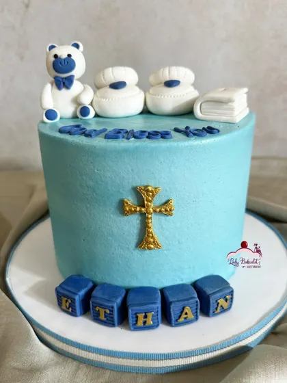 The front view of Ethan's baptism cake, showcasing the gold cross and his name in blocks.