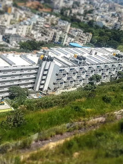 An aerial view of the Mars Mount project, showing its large scale and terraced design on a sloped site. The building's form is optimized for the topography of the location.